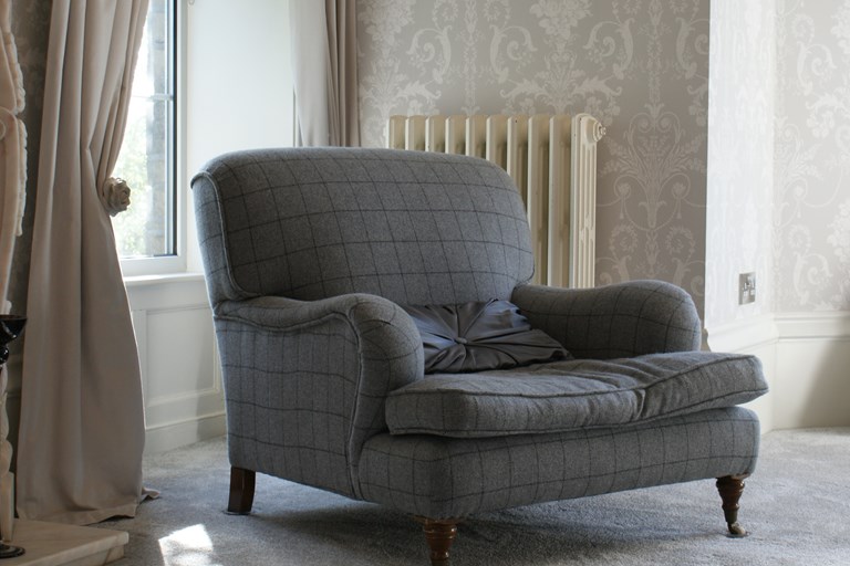 Armchair in grey fabric against backdrop of curtains