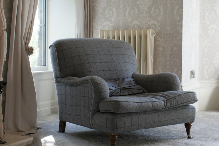 Armchair in grey fabric against backdrop of curtains Armchair in grey fabric against backdrop of curtains